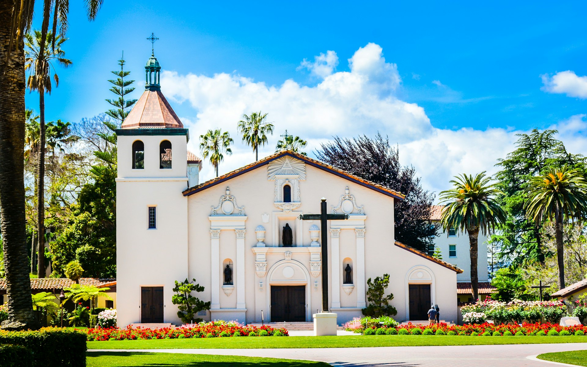 A small white church with a squat tower and a large wooden cross on the front