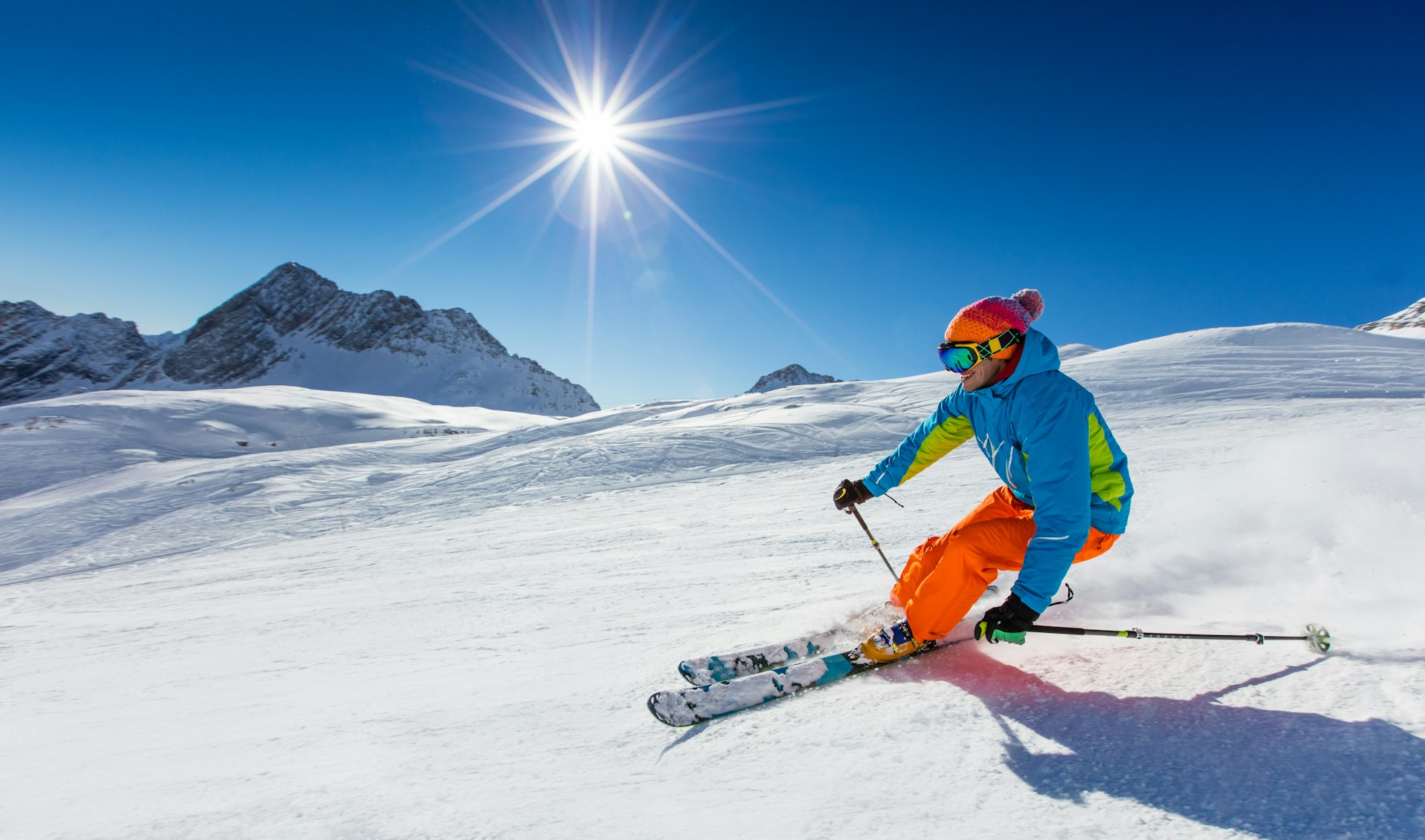 Skier skiing downhill during sunny day in high mountains in Italy 