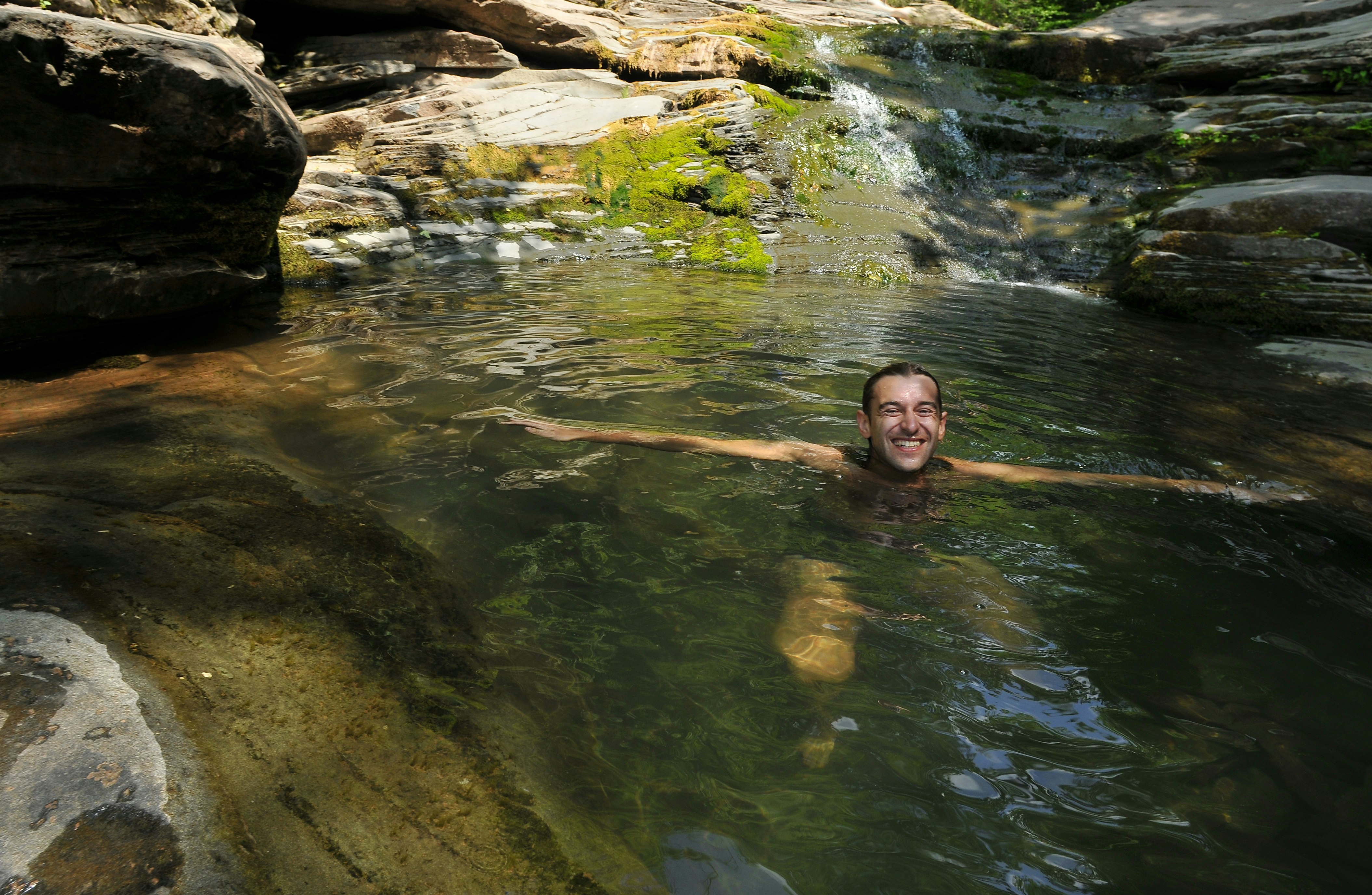 A man swimming in an oasis pool with waterfall at Catskills mountains, NY