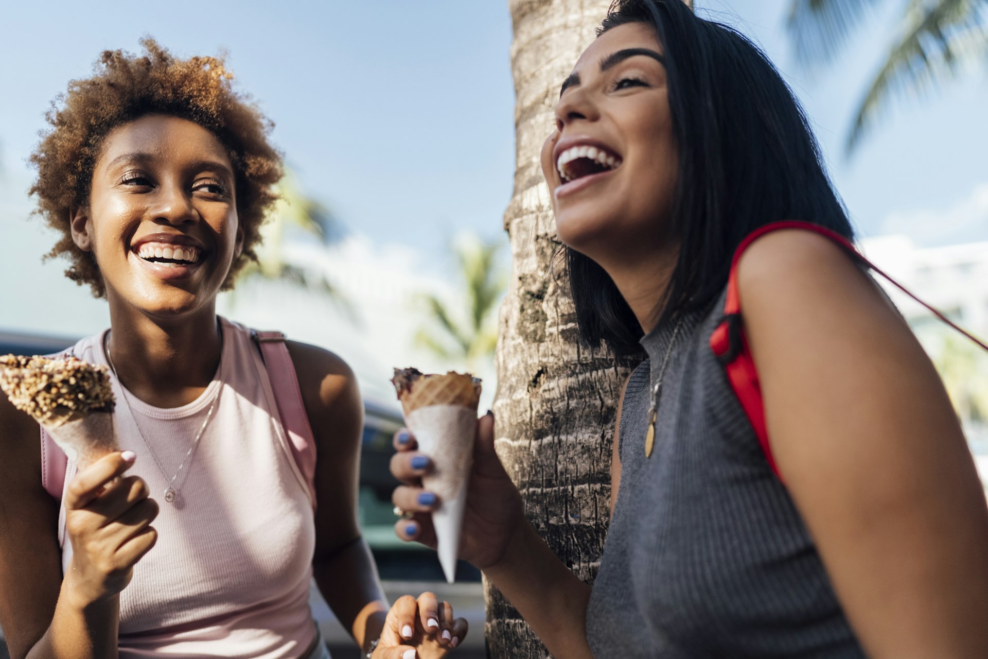 Two happy female friends with ice cream cones at a palm tree