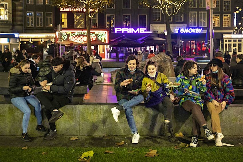 Mensen zitten op het Rembrandtplein in Amsterdam
