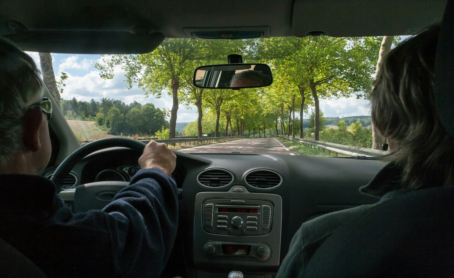 A view of the Burgundy countryside through the windscreen of a couple on a road trip