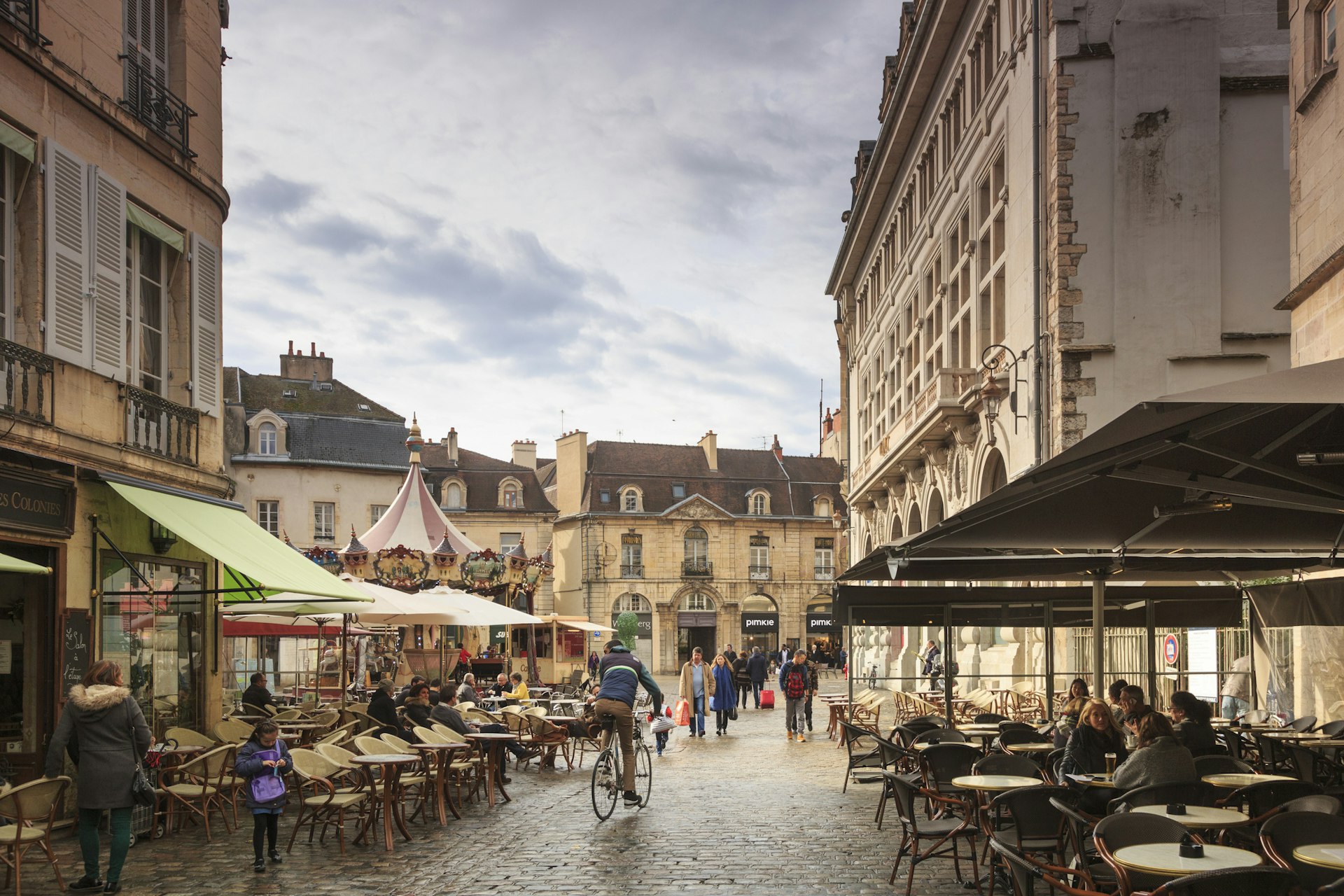 A cobbled street line with cafe tables with people socialising in Dijon, France