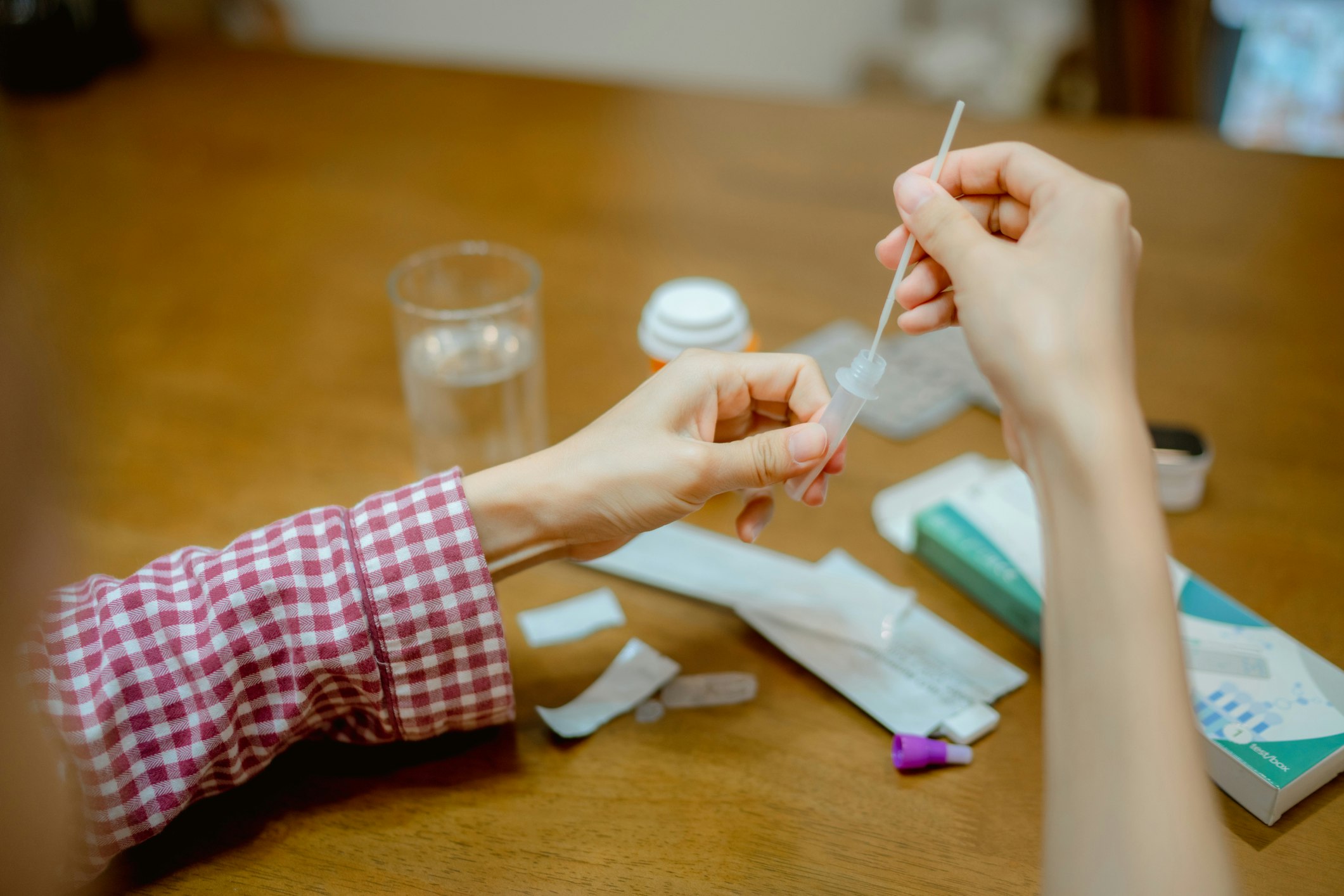 A young woman drops a COVID-19 swab in a protective plastic tube.