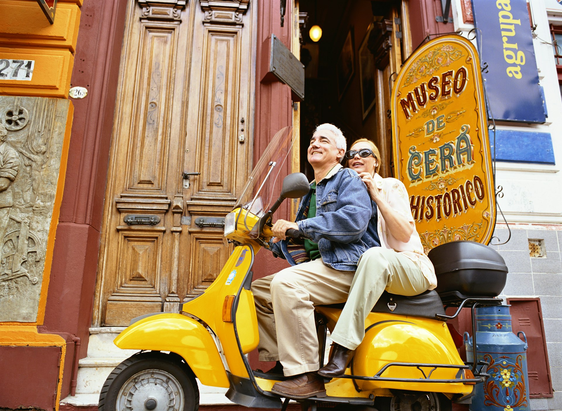 A couple sit on a scooter together outside the wax museum in Buenos Aires