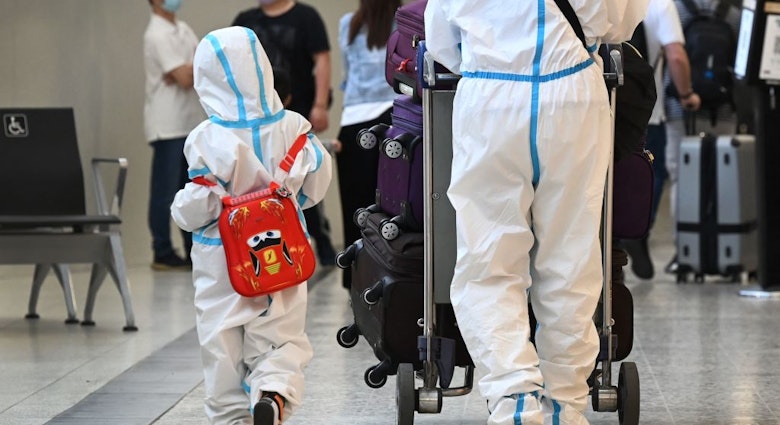 TOPSHOT - International travellers wearing personal protective equipment (PPE) arrive at Melbourne's Tullamarine Airport on November 29, 2021 as Australia records it's first cases of the Omicron variant of Covid-19. (Photo by William WEST / AFP) (Photo by WILLIAM WEST/AFP via Getty Images)