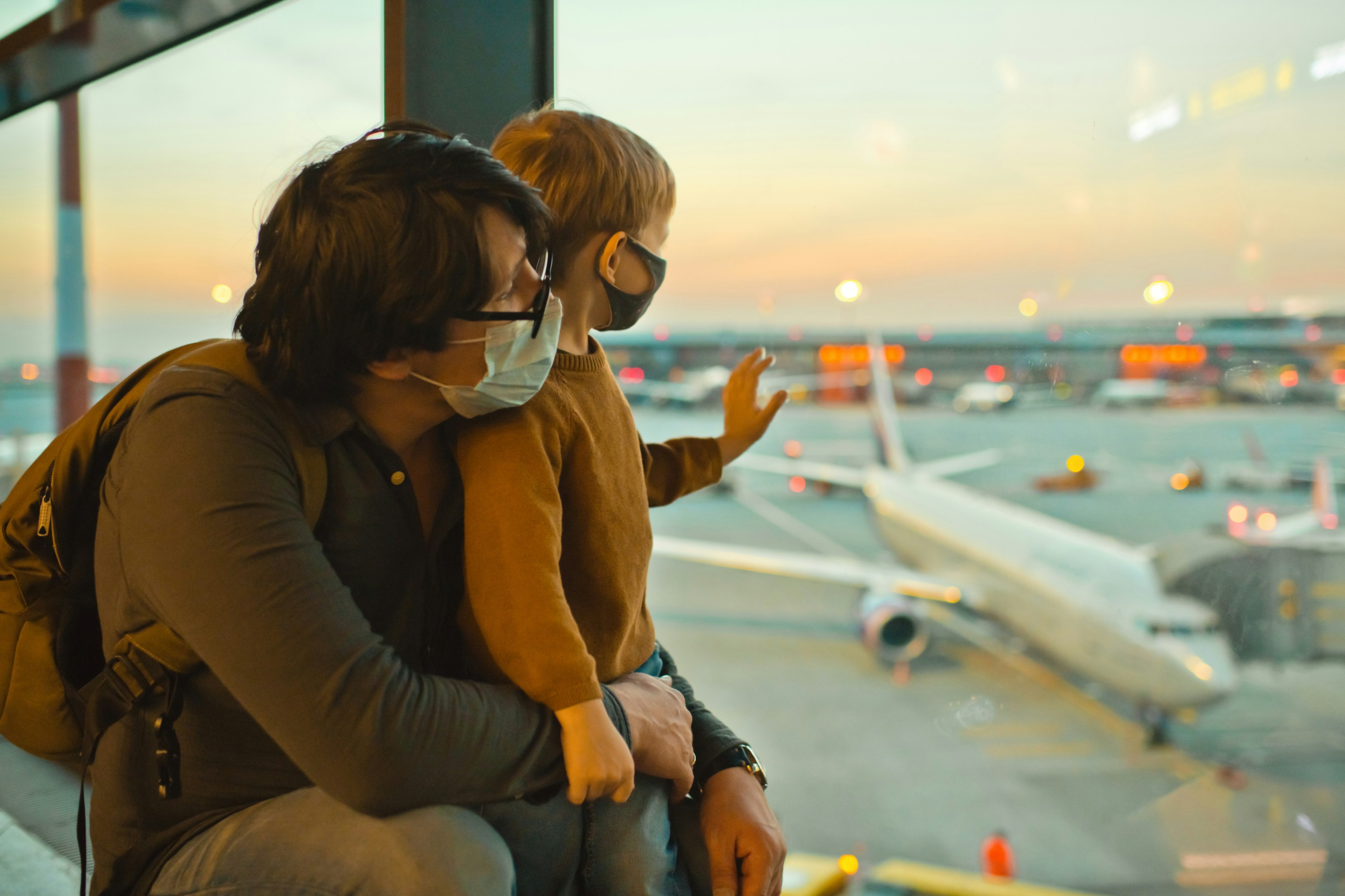 Father and son in protective face masks in airport during COVID-19 pandemic