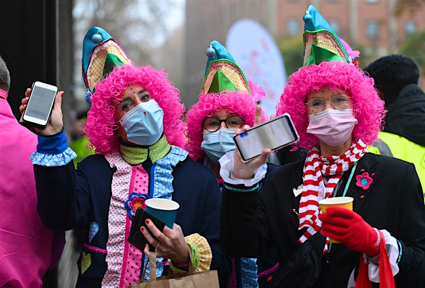 Revellers show their mobile phones displaying their vaccination certificates at the start of the Carnival season in Cologne, western Germany, on November 11, 2021. - Due to the tense Corona situation, the city of Cologne has introduced the 2G rule at the Altstadt carnival hotspots. This means that only proven vaccinated and recovered people can celebrate at carnival events and parties in pubs and in the restricted zones in the old town. 