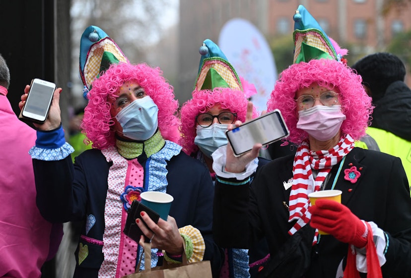 Revellers show their mobile phones displaying their vaccination certificates at the start of the Carnival season in Cologne, western Germany, on November 11, 2021. - Due to the tense Corona situation, the city of Cologne has introduced the 2G rule at the Altstadt carnival hotspots. This means that only proven vaccinated and recovered people can celebrate at carnival events and parties in pubs and in the restricted zones in the old town. (Photo by Ina FASSBENDER / AFP) (Photo by INA FASSBENDER/AFP via Getty Images)