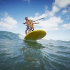A father and son riding a wave on a paddleboard on Maui