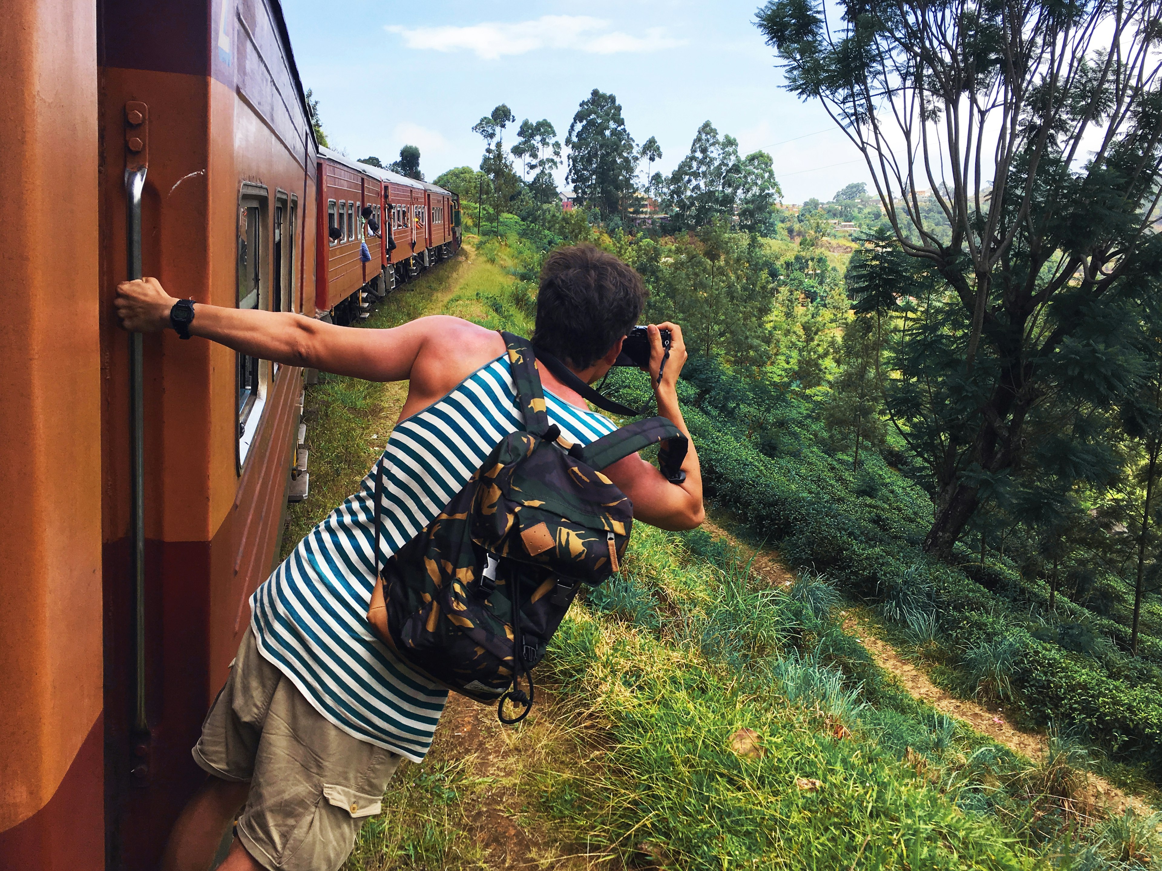 Train passenger leaning out to take a photo at Haputale, Sri Lanka