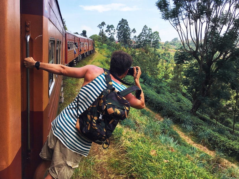 Train passenger leaning out to take a photo at Haputale, Sri Lanka