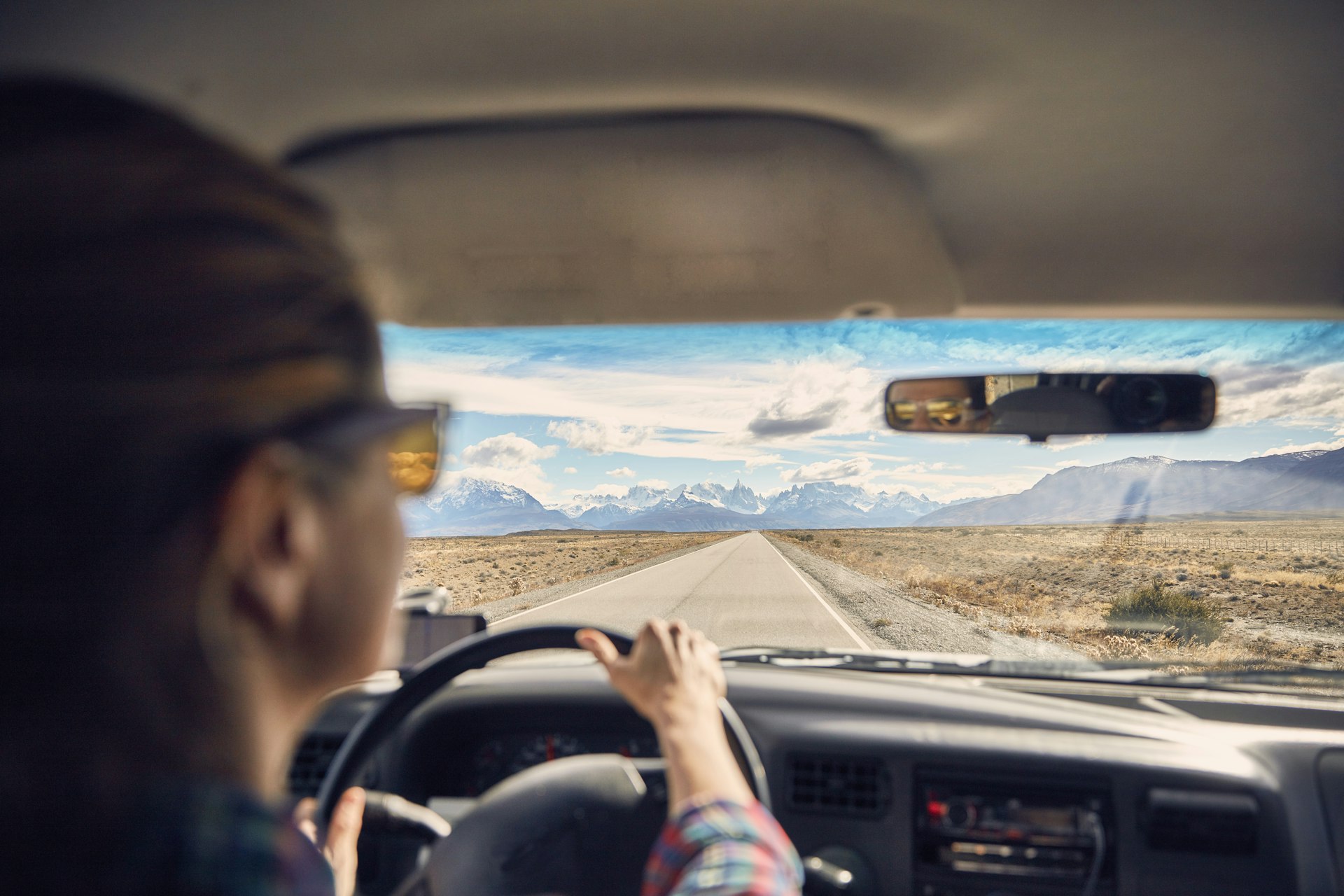 A driver's point of view out the windshield down a road towards a mountain