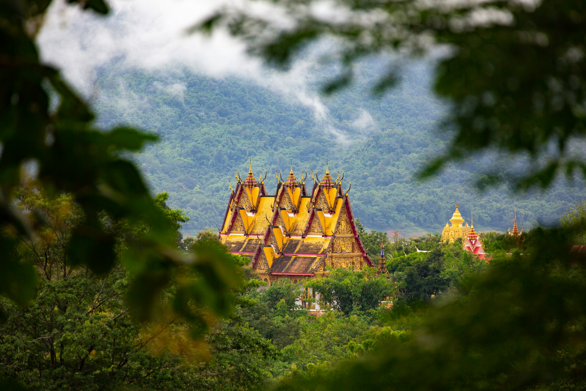Sangkhlaburi Scenic View - Wat Wang Wiwekaram Temple (and Jedi Buddhakaya in the background) in the valley of tropical rainforest and low lying cloud in Sangkhlaburi.