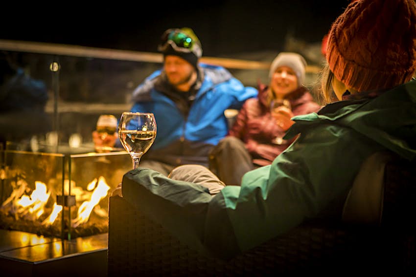 Amis assis près du feu à l'après-ski la nuit avec des boissons