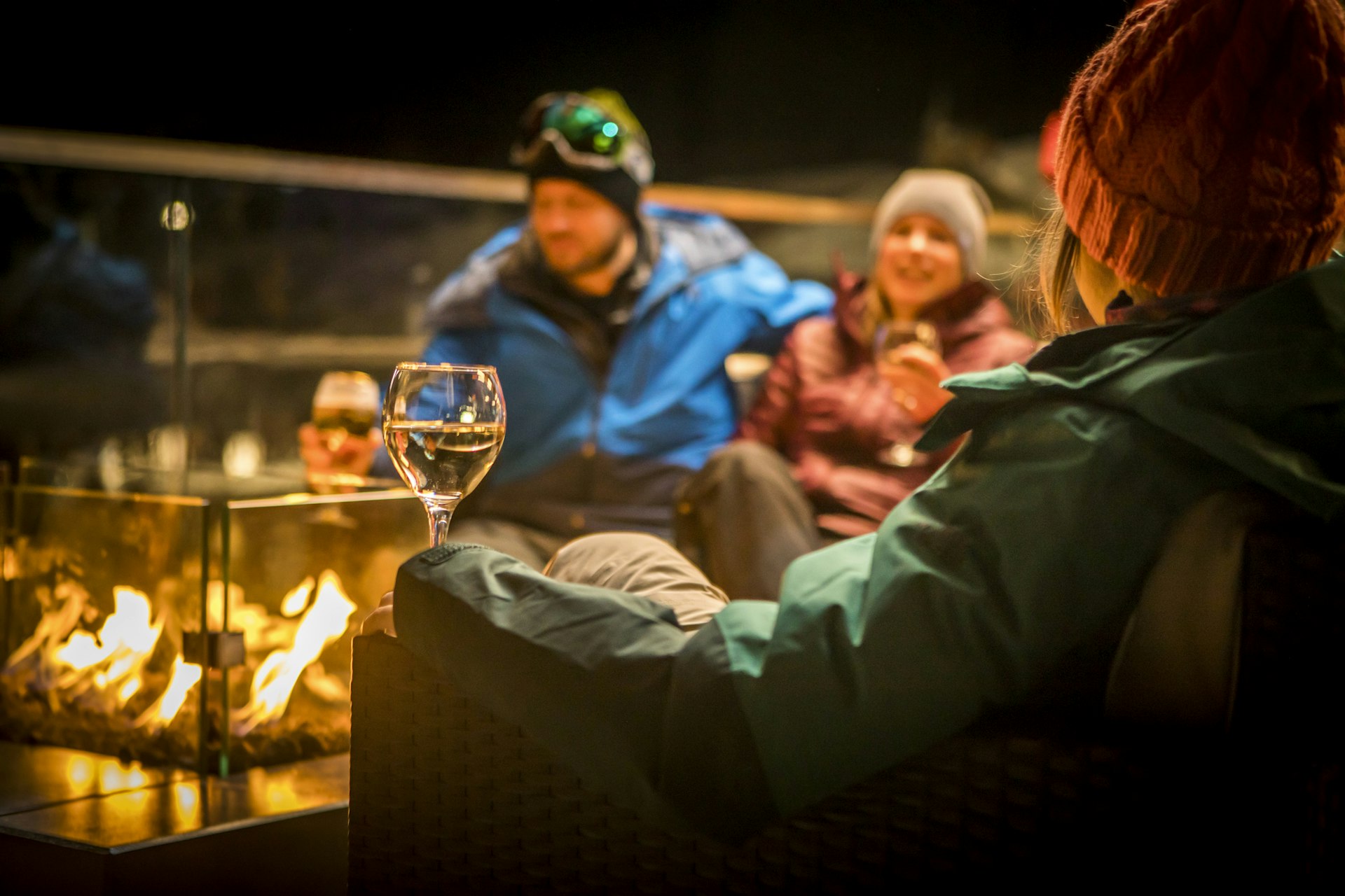 Friends sitting by fire with drinks at night with drinks in Aspen, Colorado