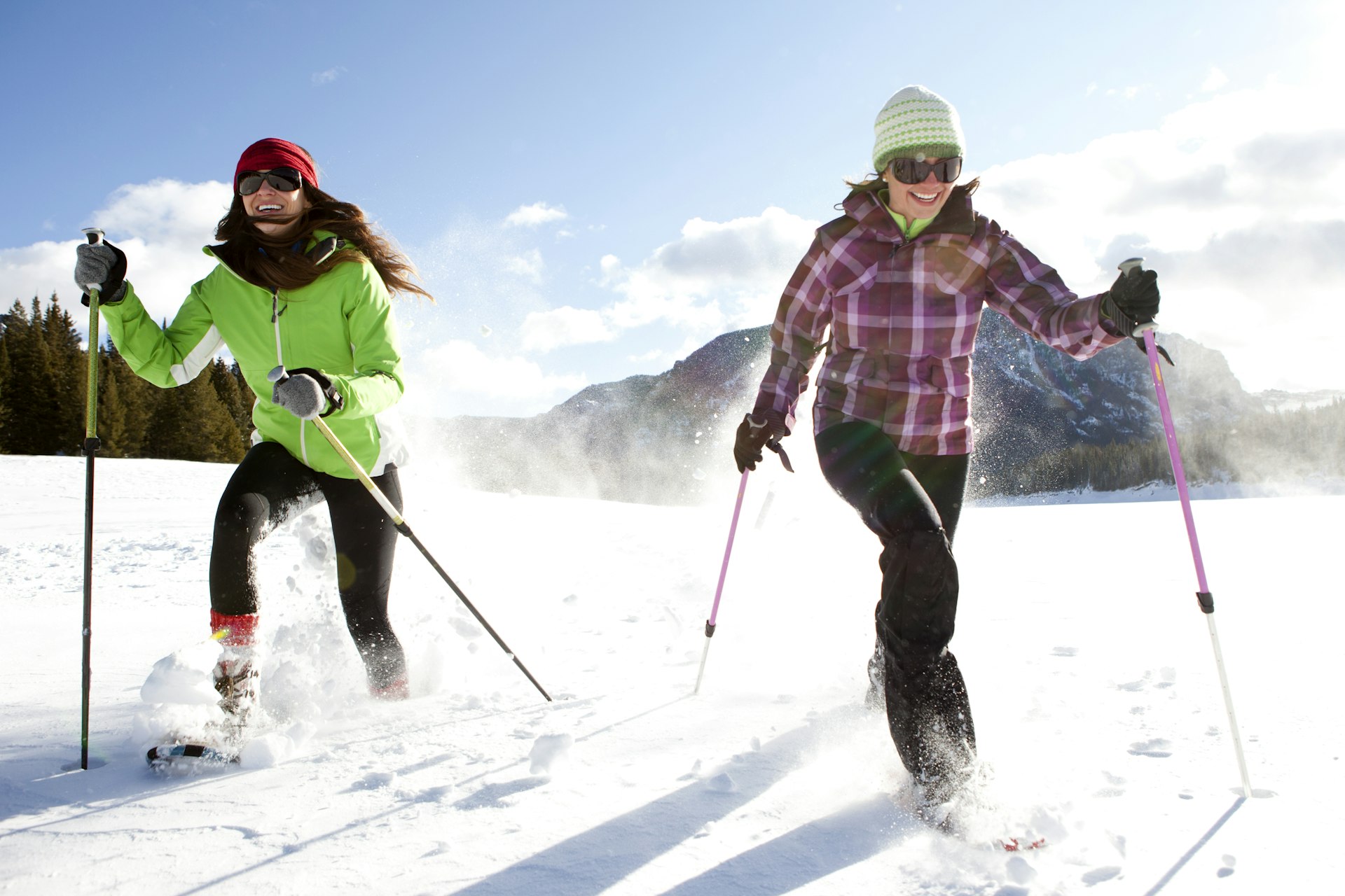 Two smiling women snowshoeing on a sunny winter day 