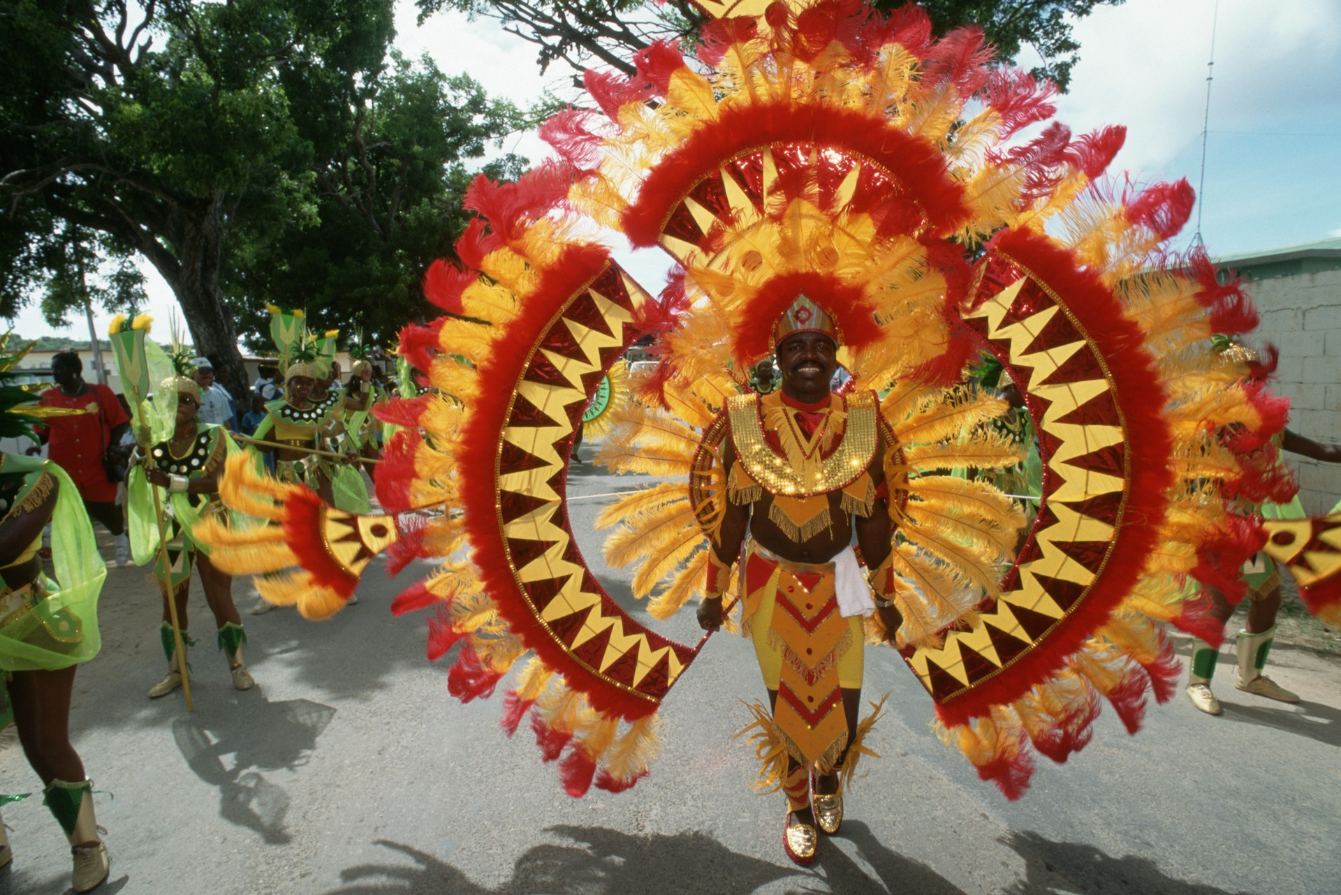 A man dressed in a red and orange feather costume for the Parade of Troupes in Anguilla