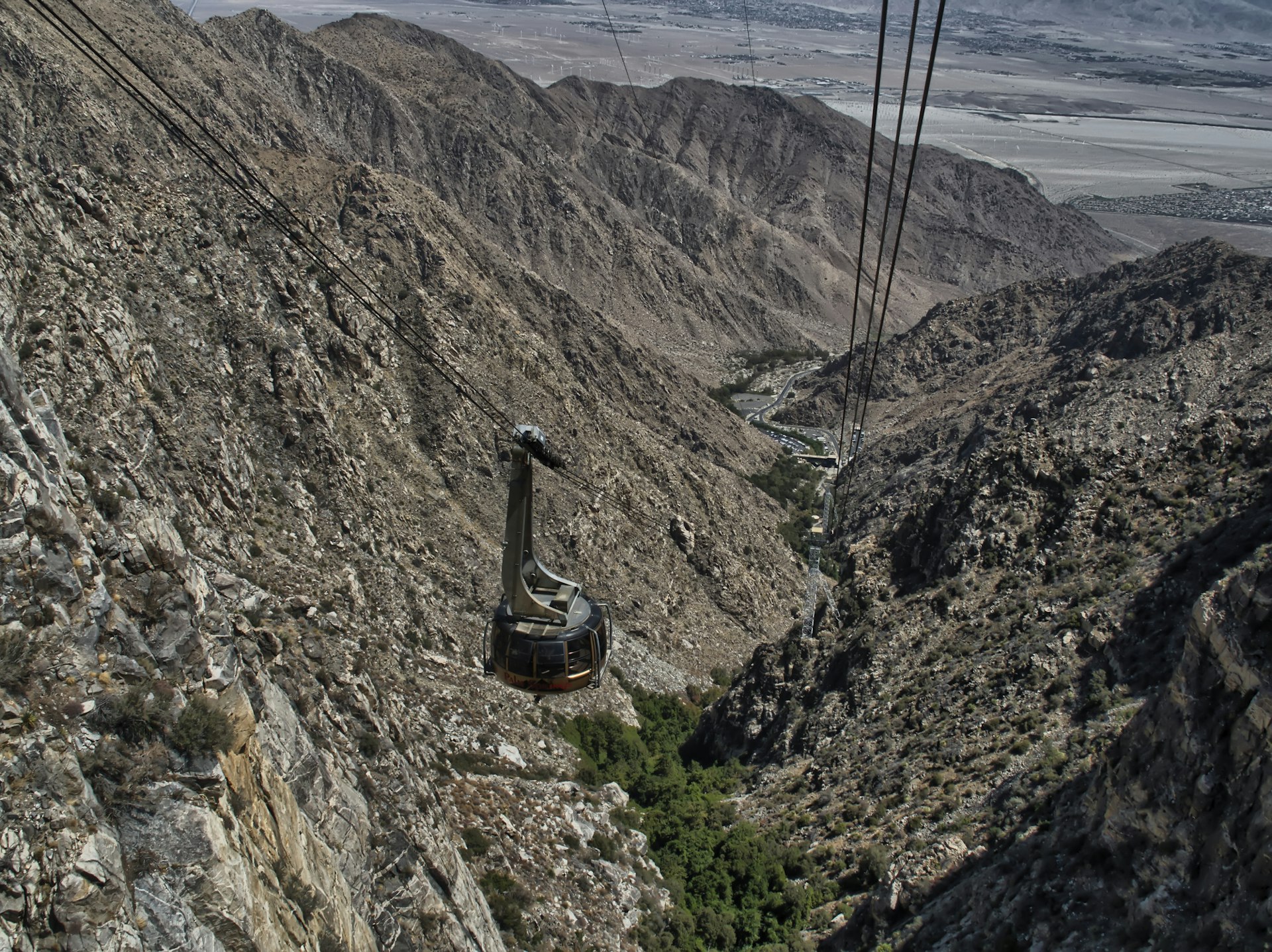 A cable car follows the route of a cleft in the rocks in a vast rocky desert landscape
