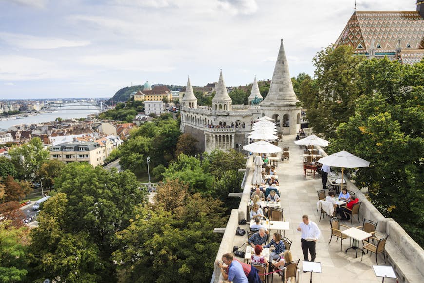 Locals eating outdoors at a restaurant next to Fisherman's bastion