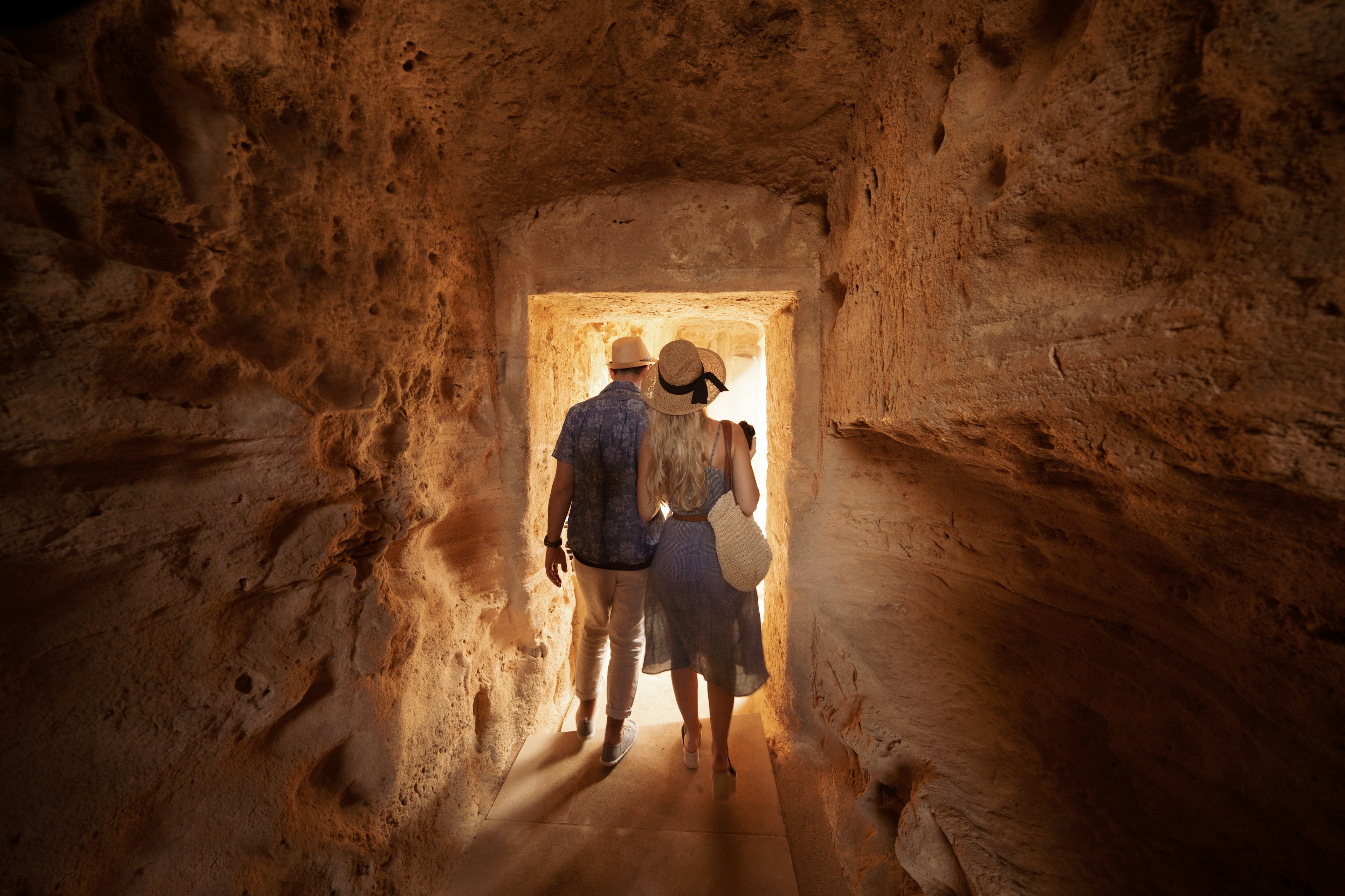 Man and woman walking through tunnel at the Tombs of the Kings
