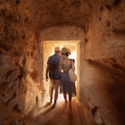 Man and woman walking through tunnel at the Tombs of the Kings