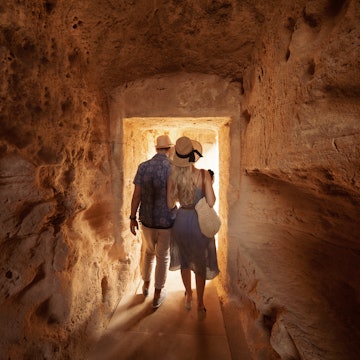 Man and woman walking through tunnel at the Tombs of the Kings