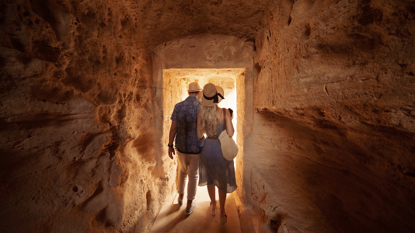 Man and woman walking through tunnel at the Tombs of the Kings