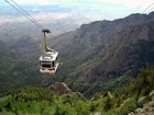 A cable car at the Sandia Peak Tramway approaching the top of Sandia Mountain, with the city of Albuquerque in the background.
