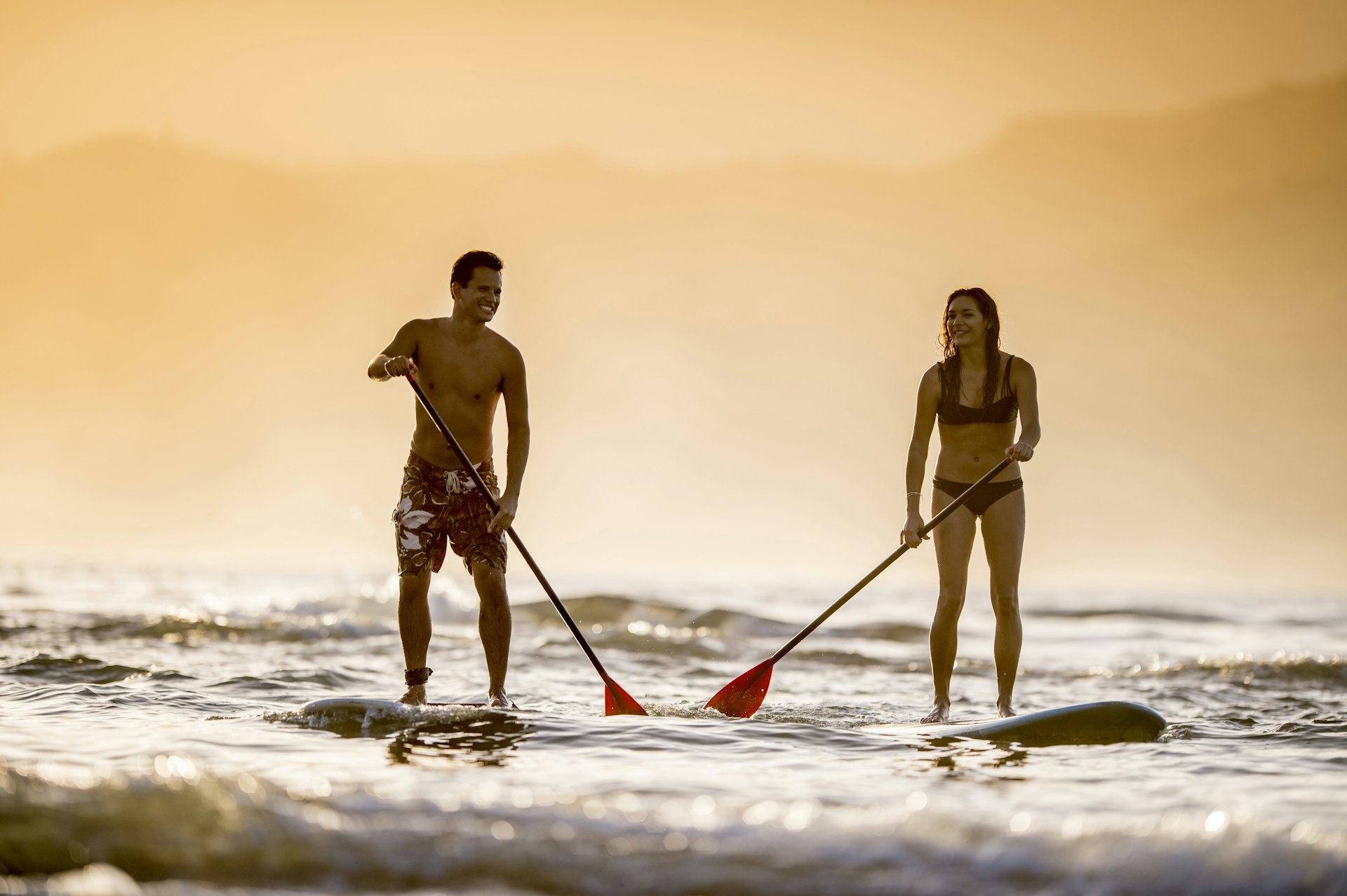 Couple stand up paddleboarding off Kaua'i