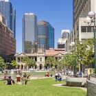 Brisbane, Australia - September 26, 2016: View of people sitting in lawn enjoying the sunshine in Post Office Square in Brisbane during lunchtime with skyline in the background.