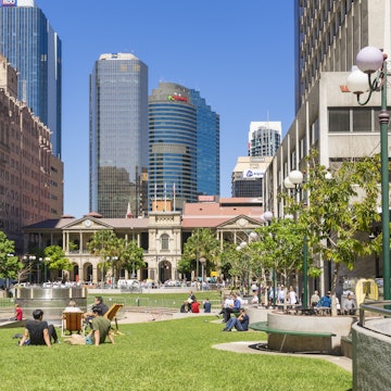 Brisbane, Australia - September 26, 2016: View of people sitting in lawn enjoying the sunshine in Post Office Square in Brisbane during lunchtime with skyline in the background.