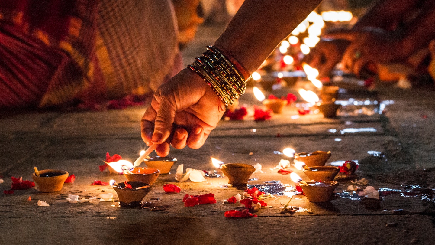 Close-up of a hand lighting incense on the ground at night in Varanasi.
