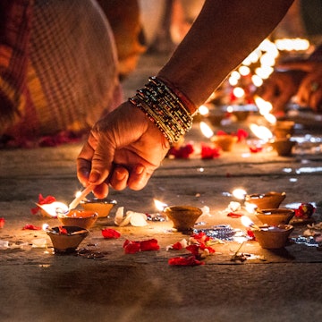 Close-up of a hand lighting incense on the ground at night in Varanasi.