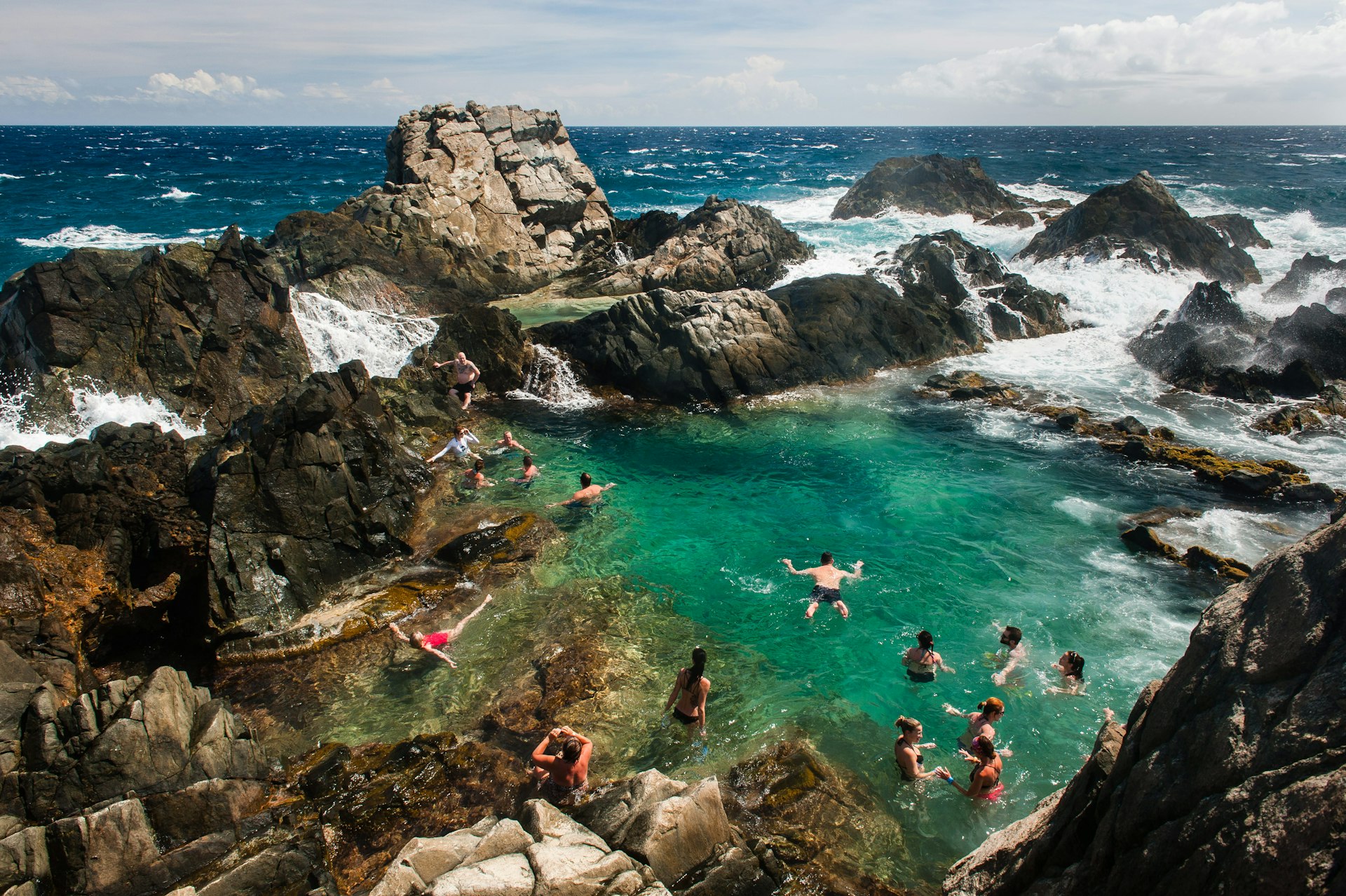 Visitors swimming in a protected rock pool on the north coast of Aruba.