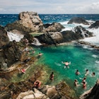 Visitors swimming in a protected rock pool on the north coast of Aruba.