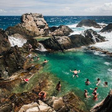 Visitors swimming in a protected rock pool on the north coast of Aruba.