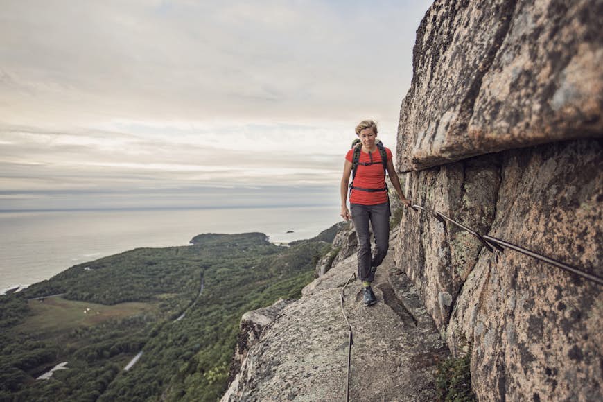 Woman hiking along cliff edge, Acadia National Park, Maine, USA