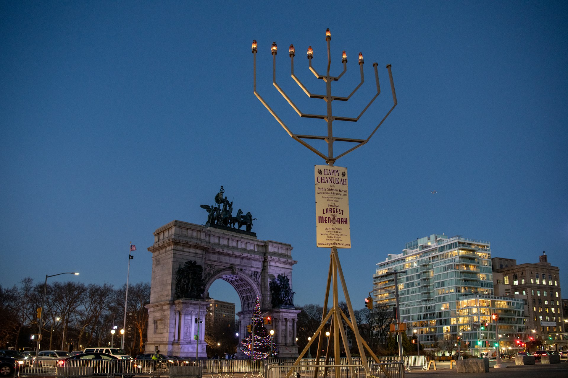 A giant menorah at dusk, towering over Brooklyn's Grand Army Plaza with the arch in the background