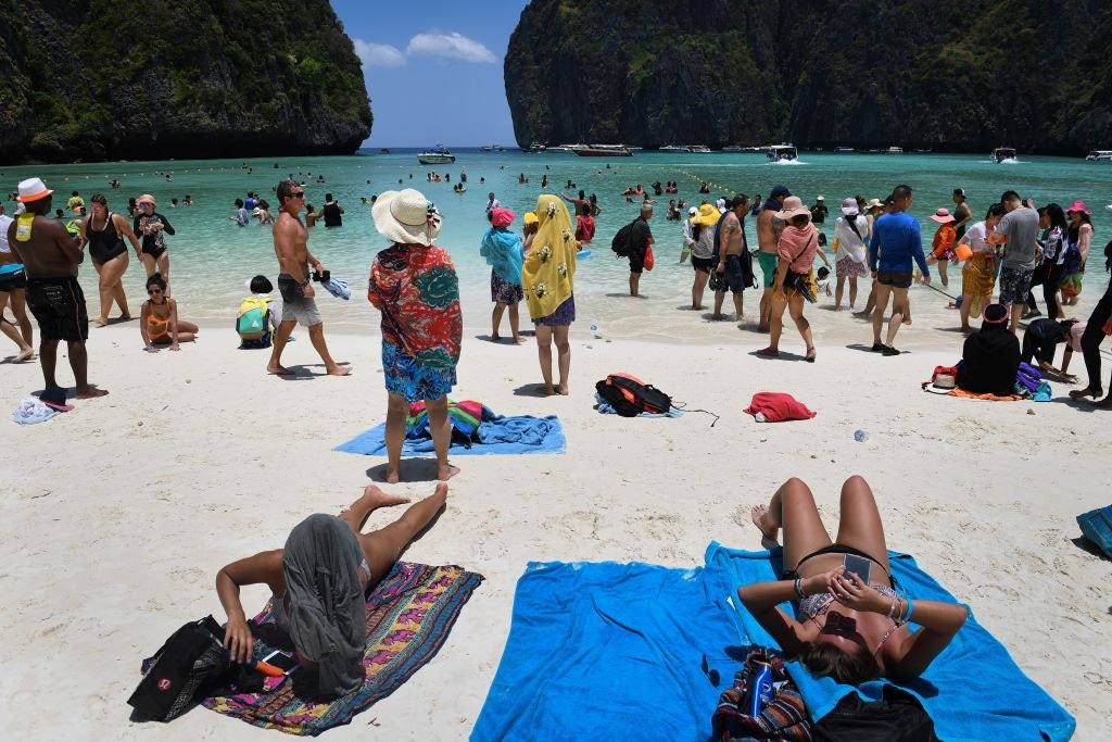 Tourists sunbathing and walking on Maya Bay