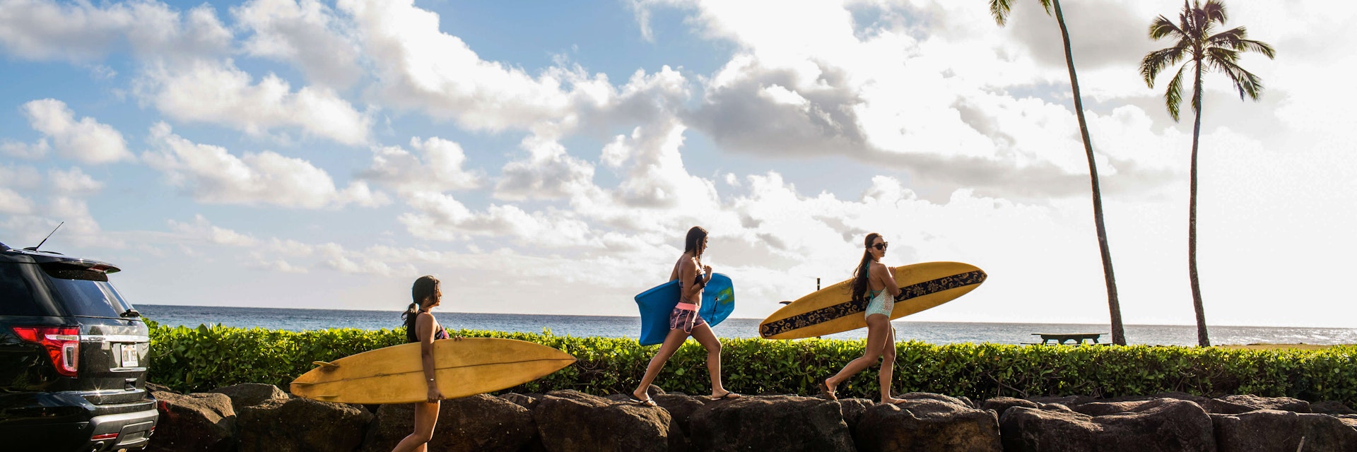 Pacific Islander surfers carry their boards to the water.