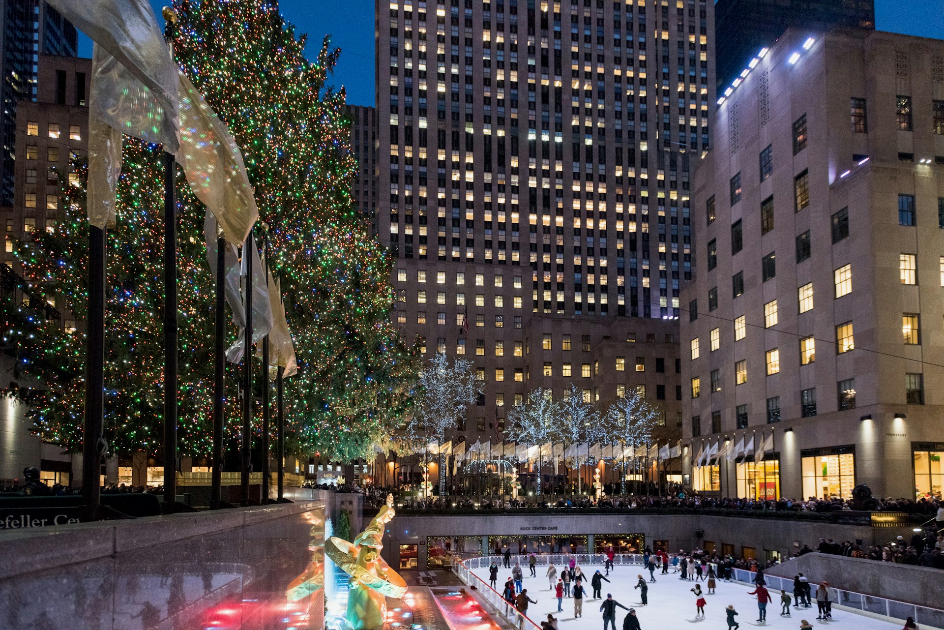 A distant shot of people skating at Rockefeller Center with the Christmas tree in view