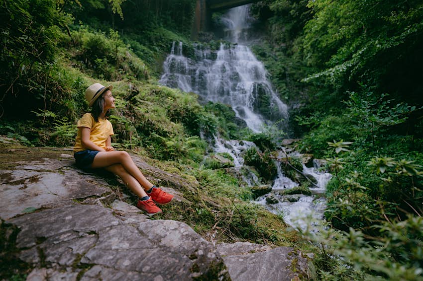 Young girl in forest with waterfall, Kochi, Shikoku, Japan