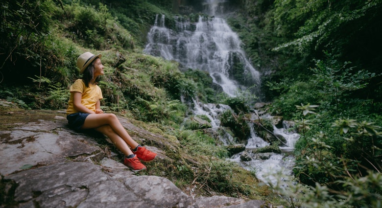 Young girl in forest with waterfall, Kochi, Shikoku, Japan