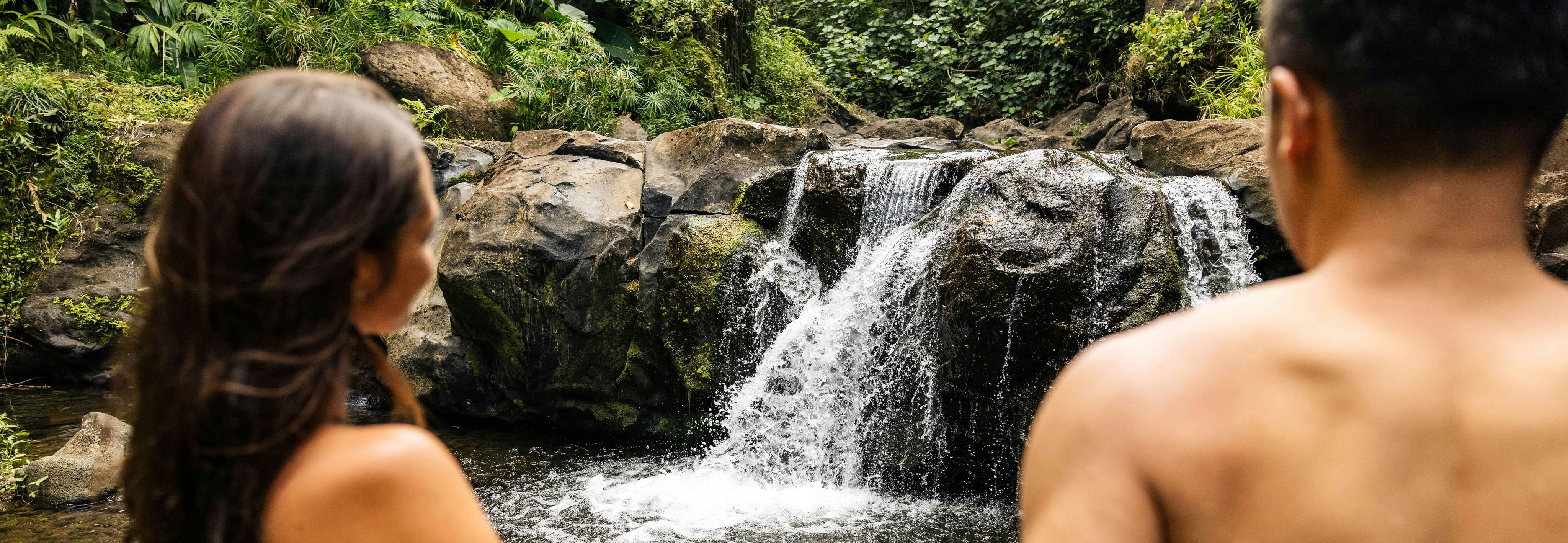 Visitors relax at a small waterfalll after a day of volunteering Papahana Kuaola Oahu Hawaii.