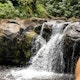 Visitors relax at a small waterfalll after a day of volunteering Papahana Kuaola Oahu Hawaii.