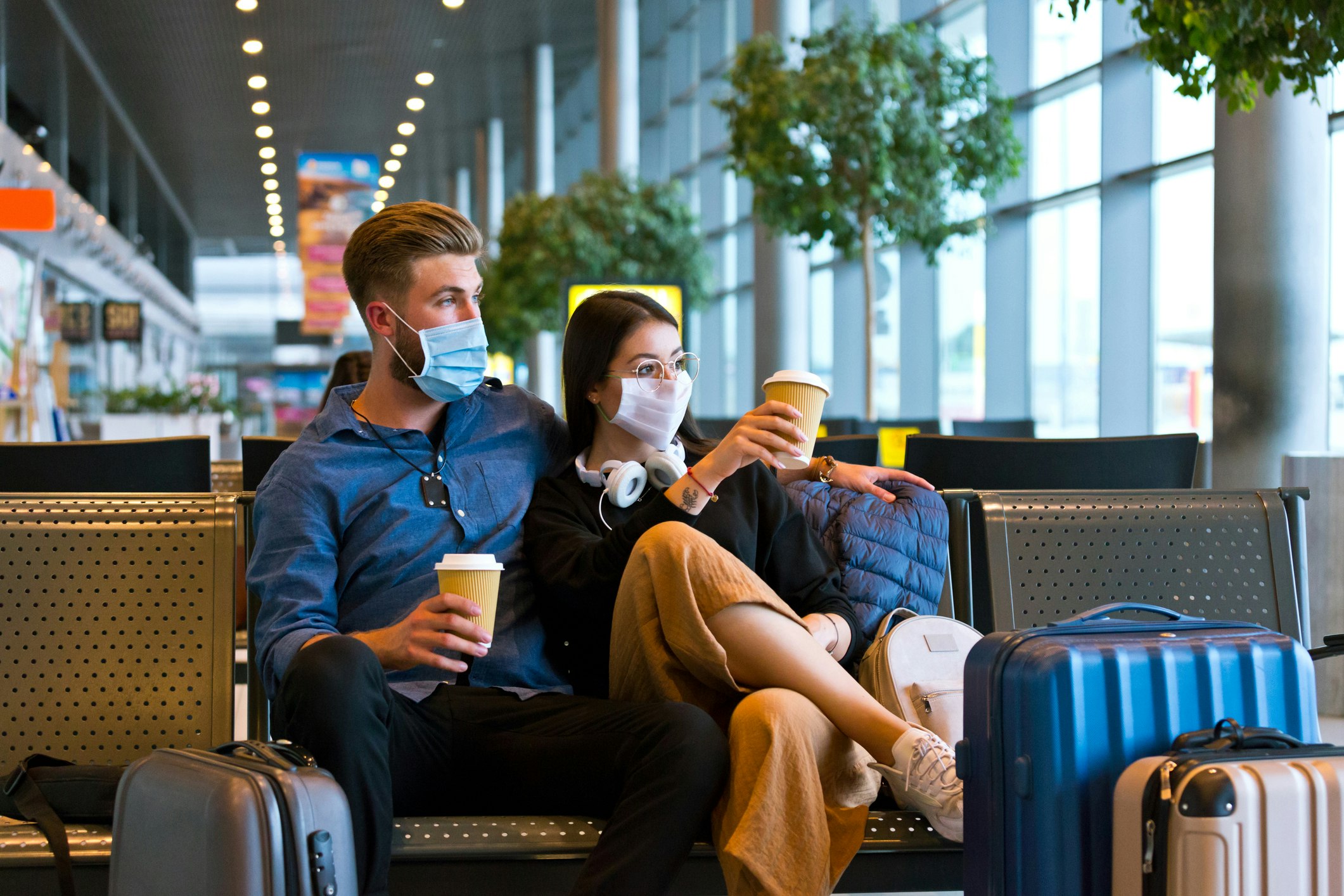 Young couple wearing N95 face masks waiting in airport area