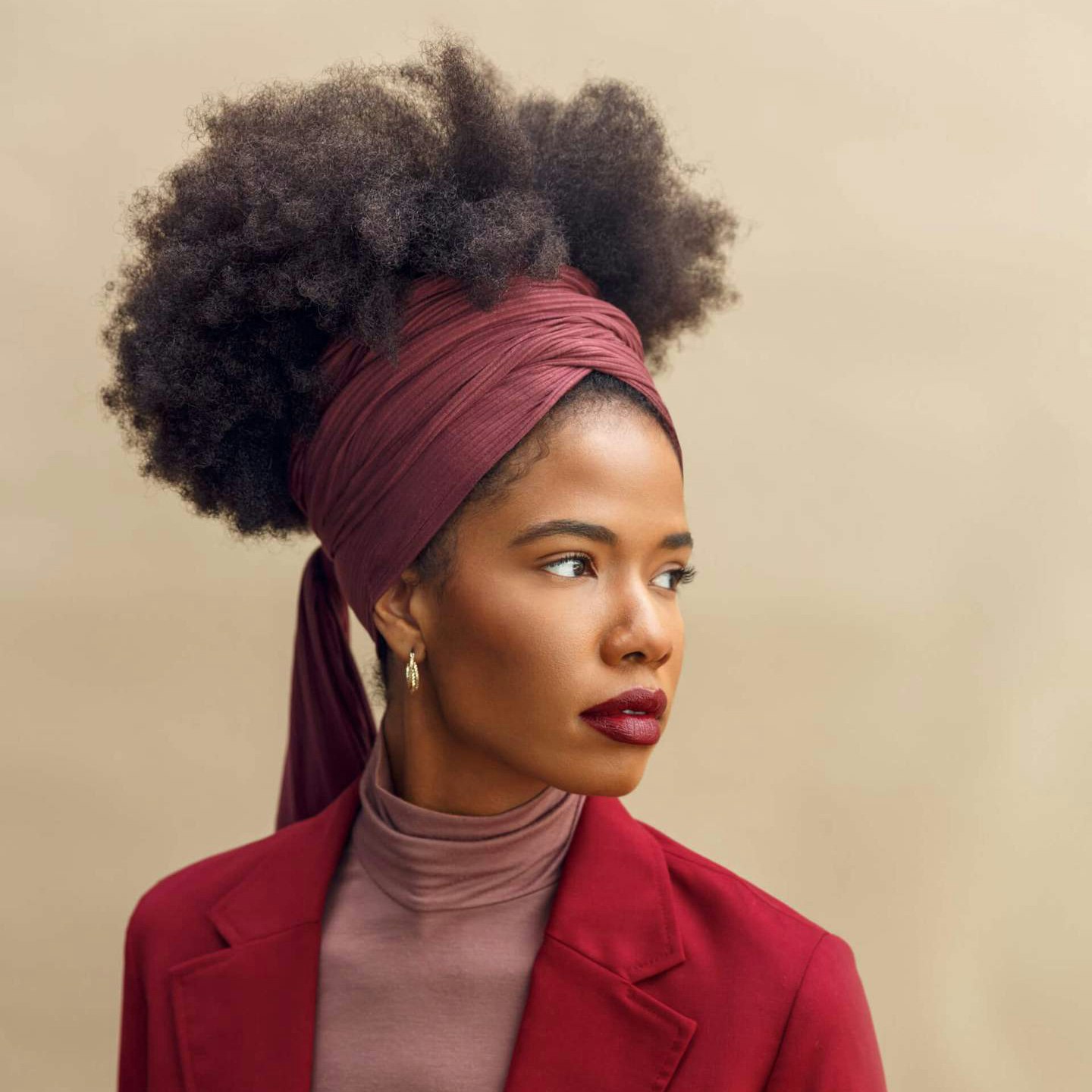 A Black woman with natural hair wearing a bright-red headwrap