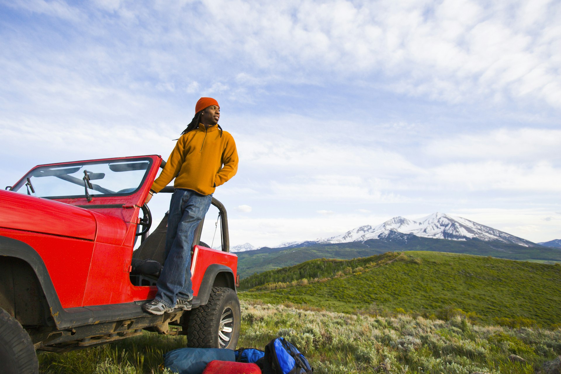 A man stands on a 4x4 looking to the Rocky Mountains of Colorado