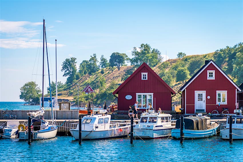 Red boathouses and sailboats in Ven, Sweden, Bäckviken harbor.